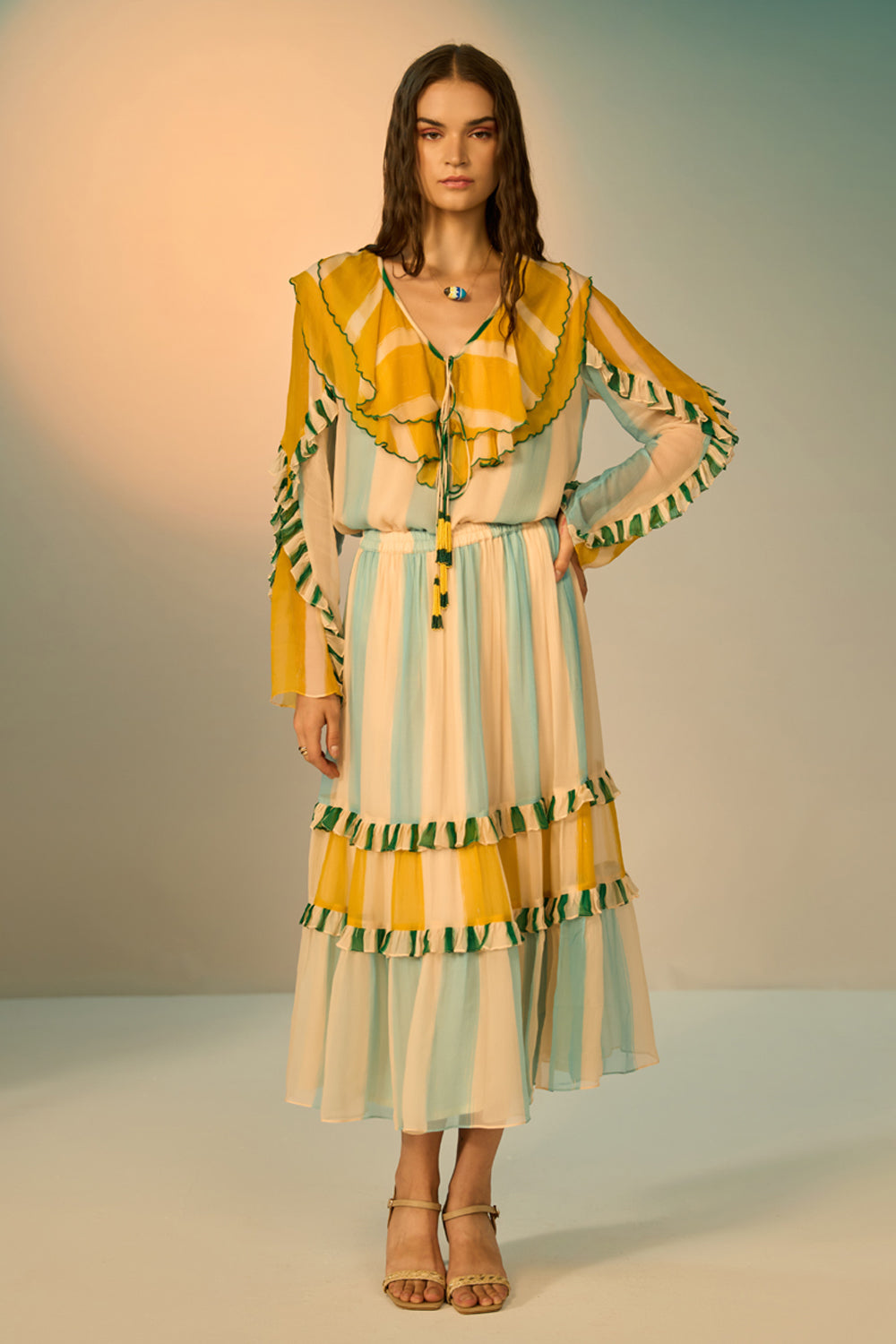 Woman wearing a colorful dress with ruffled sleeves against a neutral background