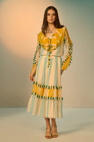 Woman wearing a colorful dress with ruffled details against a neutral background