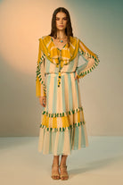 Woman wearing a colorful dress with ruffled sleeves against a neutral background