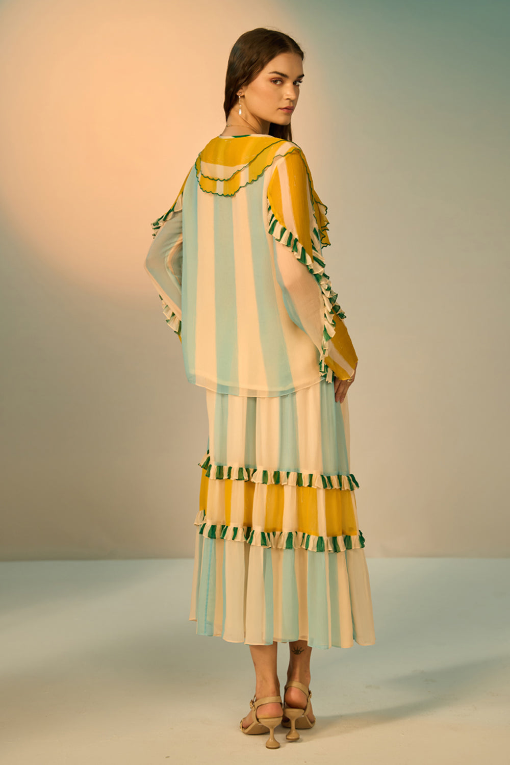 Woman wearing a colorful striped dress with a matching shawl against a neutral background